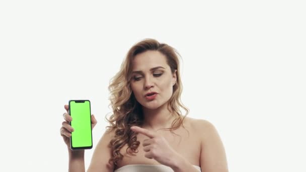 Несчастная женщина указывает пальцем на зеленый экран смартфона — стоковое видео
