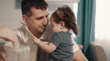 Mutfak masasında oturan ailesi ile çevrili bebek kız