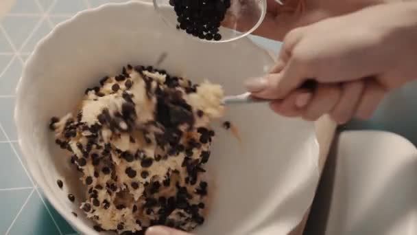 Mãe e filho adicionam chocolate à massa de biscoito, close-up — Vídeo de Stock