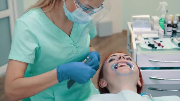 Zahnärztin wählt Zahnfarbe für Bleichverfahren.