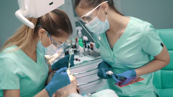 Γυναίκα οδοντίατρος με βοηθός διενεργεί λεύκανση δοντιών διαδικασία. — Αρχείο Βίντεο