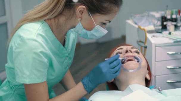 Молода жінка сидить у кріслі на прийомі у стоматолога — стокове відео