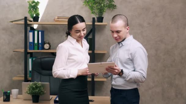 Homme et femme regardent l'écran de la tablette et mènent la discussion — Video