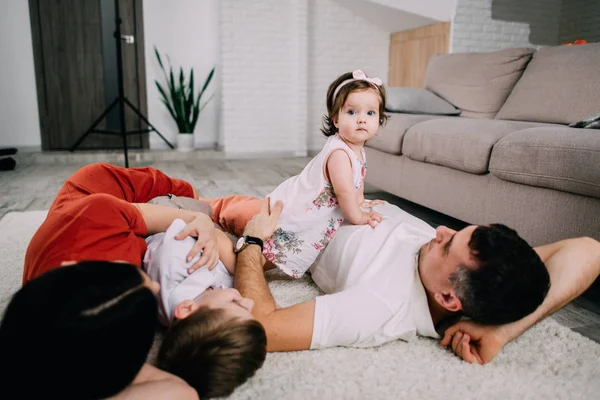 Liten flicka leker med hennes familj på golvet hemma — Stockfoto