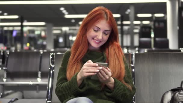 Молодая женщина пользуется телефоном в терминале аэропорта — стоковое видео