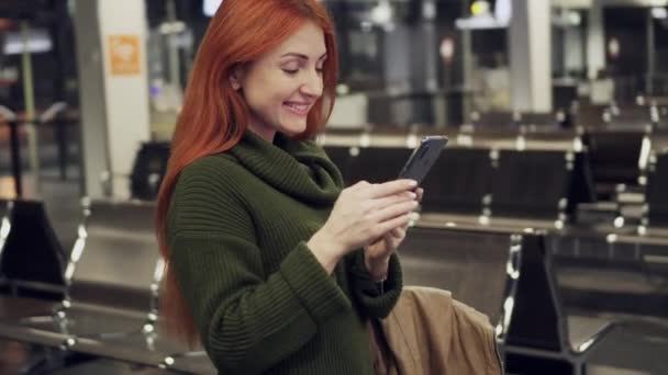 Mujer viajero se para en el aeropuerto y utiliza smartphone — Vídeo de stock