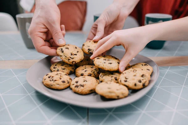 Руки беруть свіже печиво з тарілки, крупним планом — стокове фото