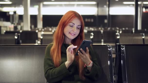 Joven mujer utiliza el teléfono en la terminal del aeropuerto — Vídeo de stock