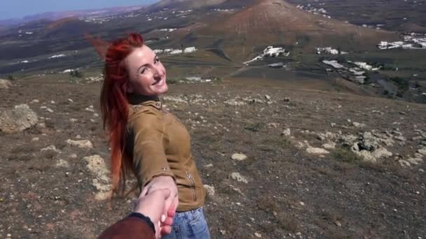 Mujer joven está a mano de su compañero en la cima de la montaña — Vídeo de stock