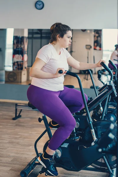 Fat woman intensely exercising on stationary bike — Stock Photo, Image