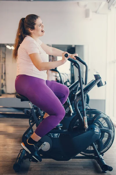 Fat woman intensely exercising on stationary bike — Stock Photo, Image