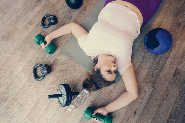 Κουρασμένη χοντρή γυναίκα ξαπλωμένη στο πάτωμα στο γυμναστήριο — Φωτογραφία Αρχείου