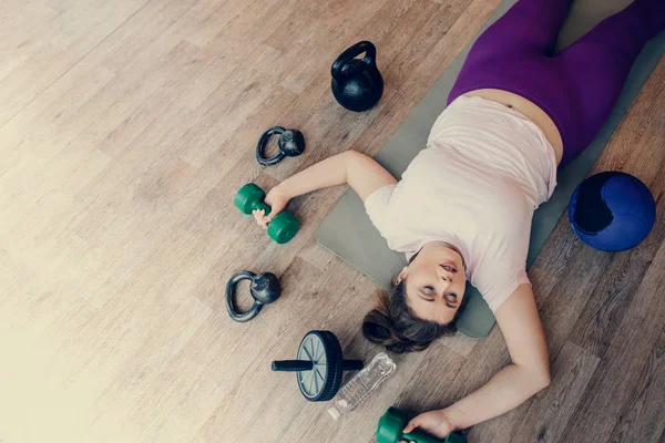 Tyk kvinde liggende udmattet på gulvet i fitness klub - Stock-foto