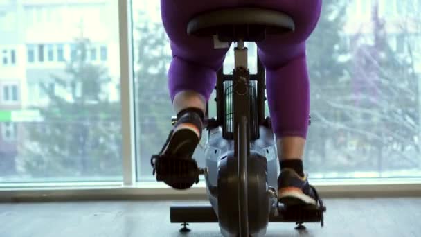Fet kvinna intensivt utövar på stillastående cykel — Stockvideo
