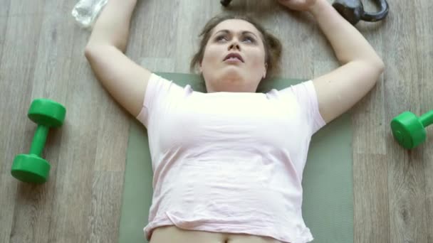 Mulher gorda deitada exausta no chão no clube de fitness — Vídeo de Stock