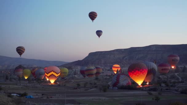 GOREME, TURQUÍA - 1 DE NOVIEMBRE DE 2018: lotes de globos de colores comienzan a volar sobre el valle en el crepúsculo antes del amanecer — Vídeos de Stock