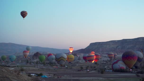 GOREME, TURQUIA - NOVEMBRO 1, 2018: muitos balões coloridos começam a voar sobre o vale — Vídeo de Stock