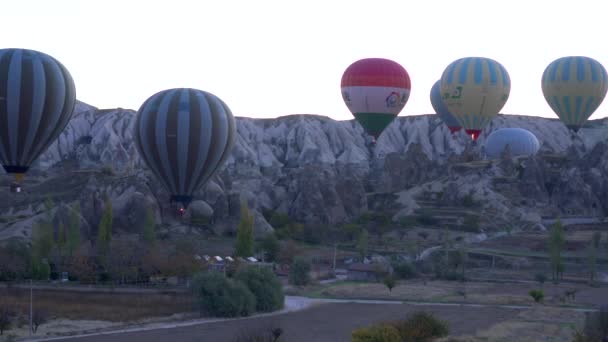 Goreme, Turkiet-november 1, 2018: färgglada varma ballonger flyga över stenar — Stockvideo