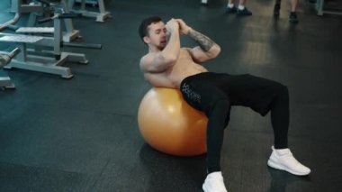 Genç kas adam spor topu kullanarak AB kasları trenler