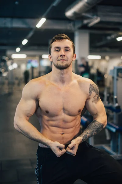 Young athletic man with naked torso standing in gym — Stock Photo, Image