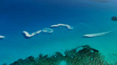 Kristal berraklığında denizde jet ski'ye binen turistlerin havadan görünümü