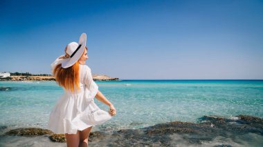 Kristal berraklığında su ile plajda duran beyaz giysiler içinde Mutlu kadın