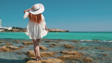 Plajda kristal berrak suyla duran kadın turist beyaz elbisesi..