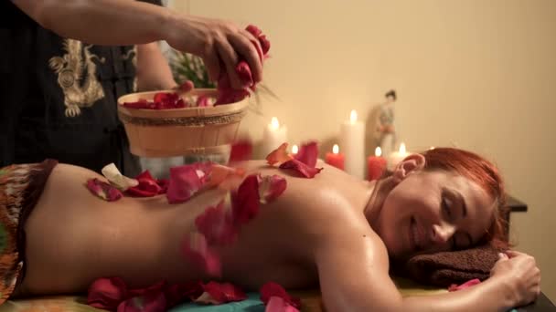 Mężczyzna masaż terapeuta wylewa płatki róż na plecach kobiet klienta po masażu w salonie Spa — Wideo stockowe