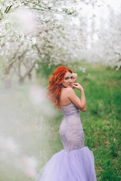 Portrait de femme aux cheveux roux heureuse dans un verger de pommiers fleuris — Photo