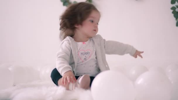 Little girl sitting on floor in bright room with white walls — Stock Video