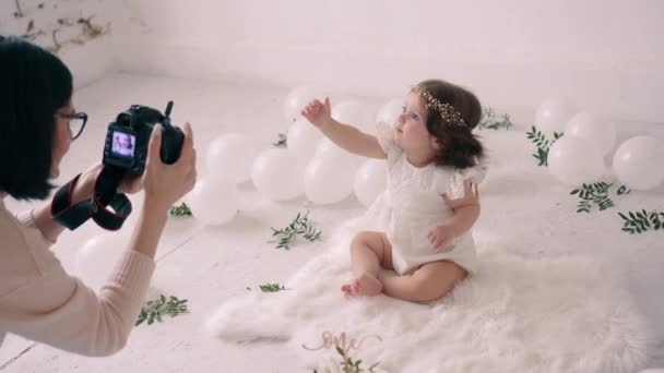 Fotógrafa toma fotos de niña en estudio de fotografía decorado . — Vídeo de stock