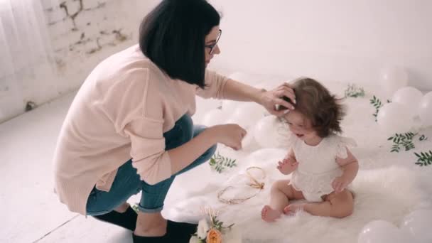 Vrouw fotograaf is kammen baby meisje alvorens het nemen van foto 's van haar in fotostudio. — Stockvideo