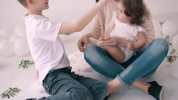 Young mother spends time with her son and one-year-old daughter at home on floor — Stockvideo