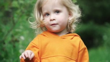 Parlak turuncu kapüşonlu küçük çocuk kamera içine bakar ve gülümsüyor