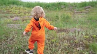 Turuncu Hoodie Little Boy Çim üzerinde çalışır