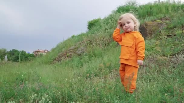 Petit garçon en sweat à capuche orange fonctionne sur herbe — Video