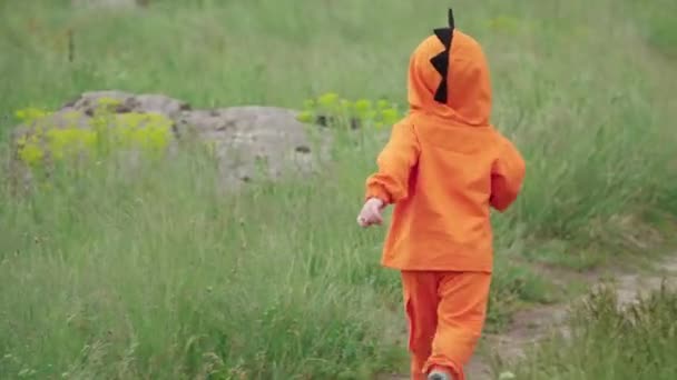 Niño pequeño con capucha naranja corre sobre hierba — Vídeos de Stock