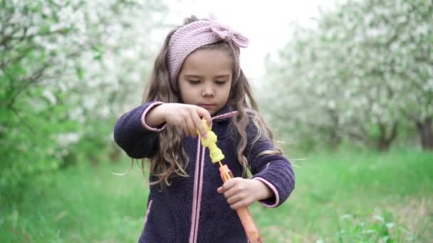 Little girl playing with soap bubbles in blooming garden, slow motion — Stock Video