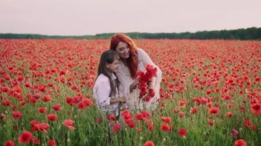 Anne ve küçük kızı çiçekli alanda haşhaş çiçekleri çelenkler yapmak