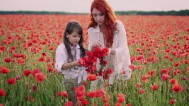 Anne ve küçük kızı çiçekli alanda haşhaş çiçekleri çelenkler yapmak