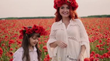 Genç Anne ve küçük kızı vahşi haşhaş çiçekleri çelenkler çiçeklenme alanında stand