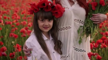 Genç Anne ve küçük kızı vahşi haşhaş çiçekleri çelenkler çiçeklenme alanında stand