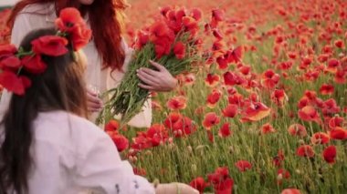 Küçük kızı ile Genç Anne çiçek açan bir alanda kırmızı haşhaş çiçekler toplamak, yakın çekim, yavaş hareket
