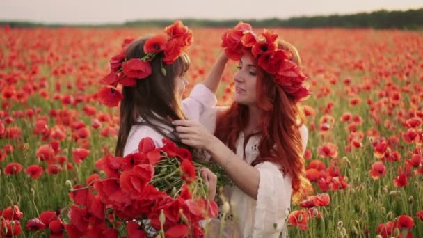 Ung mamma sätter krans av vallmo blommor på hennes döttrar huvudet, slow motion — Stockvideo