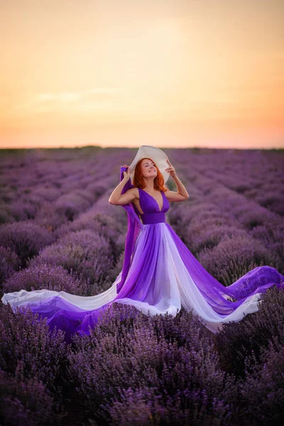 日没時にラベンダー畑に立つ豪華なドレス姿の幸せな赤い髪の女性 — ストック写真