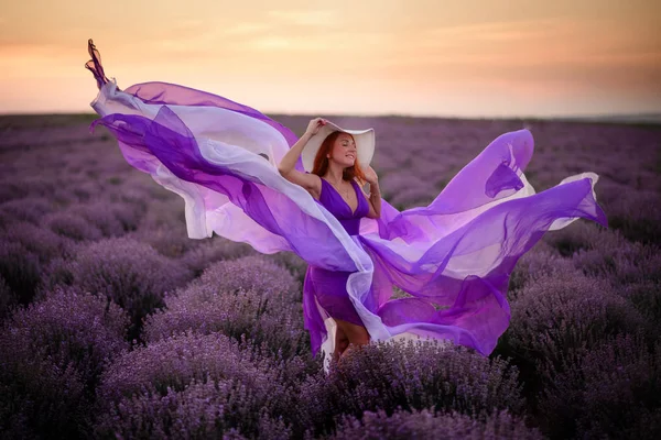 若いです幸せな女性で豪華な紫色のドレスに立ってラベンダー畑 — ストック写真