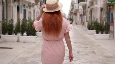 Mutlu genç kadın turist eski bir Avrupa şehrinin sokaklarında yürüyüş ve kameraya bakarak gülümseyerek