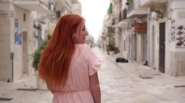 Mutlu kadın turist Polignano a Mare, İtalya sokaklarında yürüyor