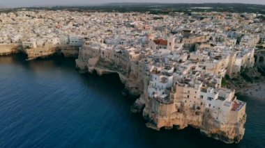 Gün batımında İtalya'nın Polignano şehrinin çatıları üzerinde uçan Bir Mare, Apulia