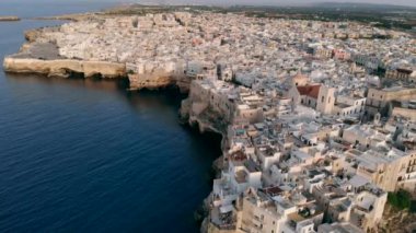 Gün batımında İtalya'nın Polignano şehrinin çatıları üzerinde uçan Bir Mare, Apulia